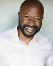 "portrait of a man with a short beard and big smile. He wears a collared shirt"